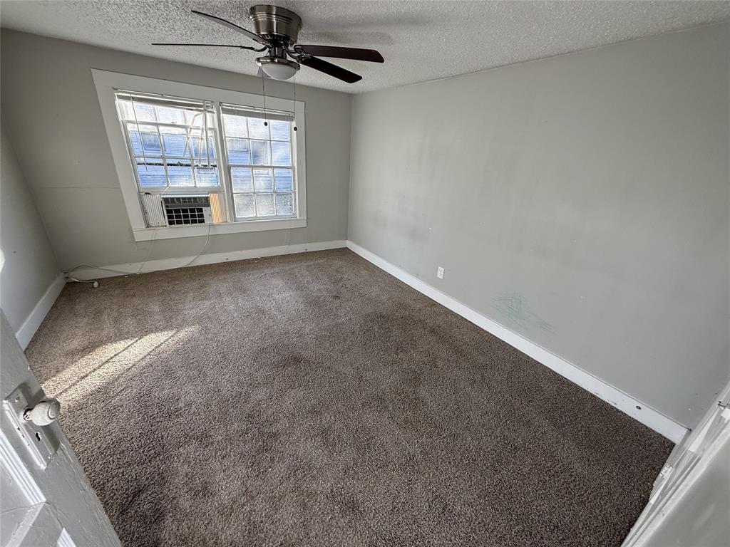 402 West 4th Street, Unit 1 Kaufman, TX 75142 - Photo 3 of 18 an empty room with a ceiling fan and windows