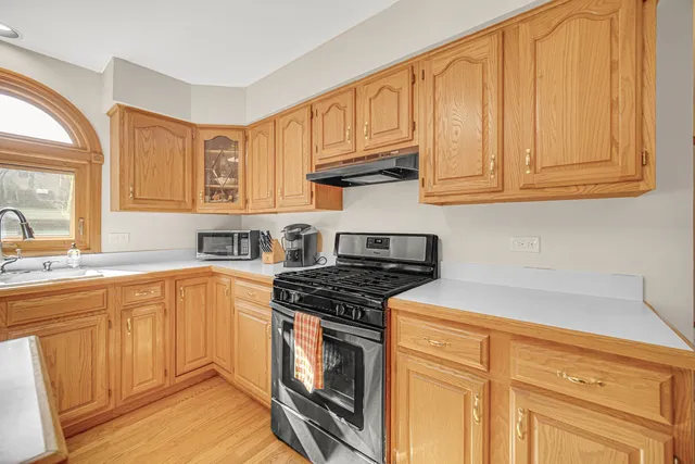 a kitchen with stainless steel appliances granite countertop a stove a sink and dishwasher with white cabinets