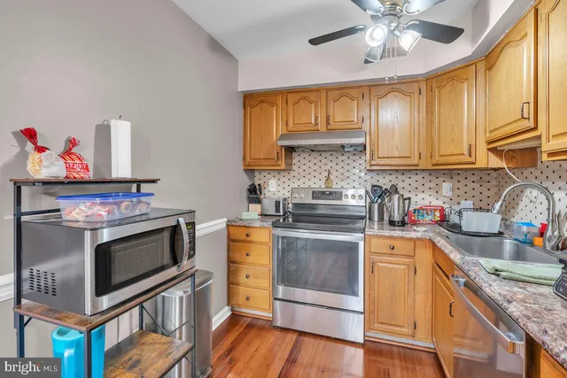 a kitchen with stainless steel appliances granite countertop a stove top oven a sink dishwasher and cabinets with wooden floor