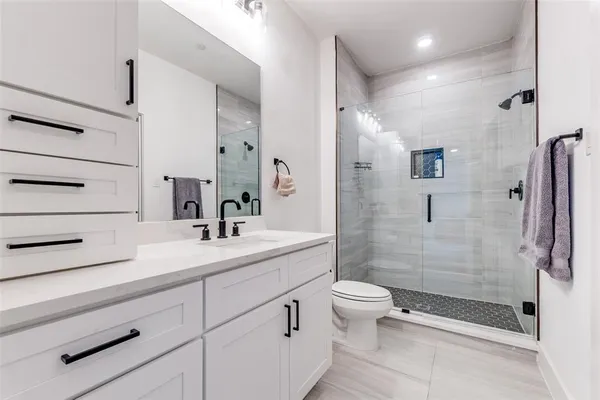 a bathroom with a shower sink vanity mirror and toilet