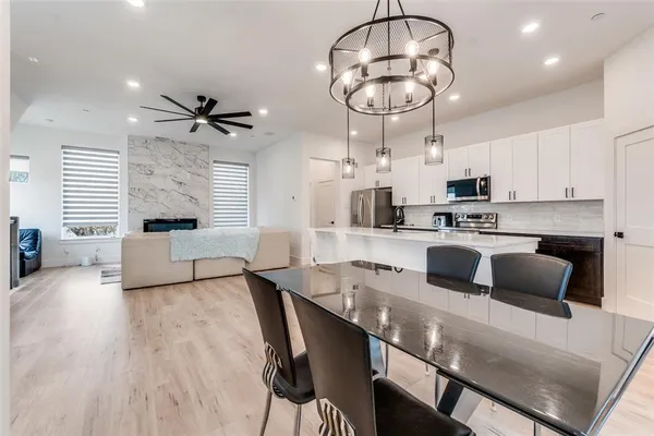 a kitchen with stainless steel appliances a stove a refrigerator a microwave a stove and white cabinets with wooden floor