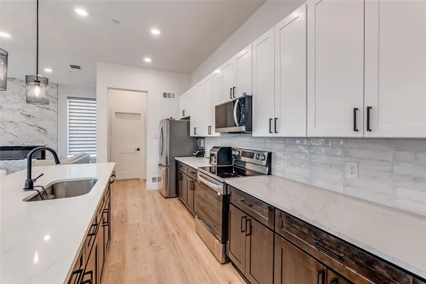 a kitchen with kitchen island granite countertop a sink a counter space appliances and cabinets
