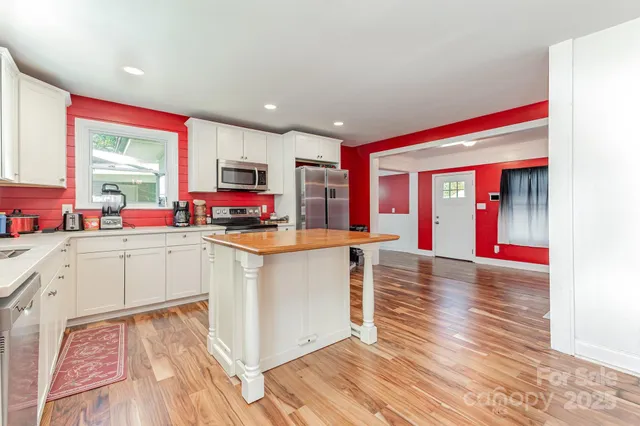a very nice looking kitchen with a large window a dining table and chairs with wooden floor
