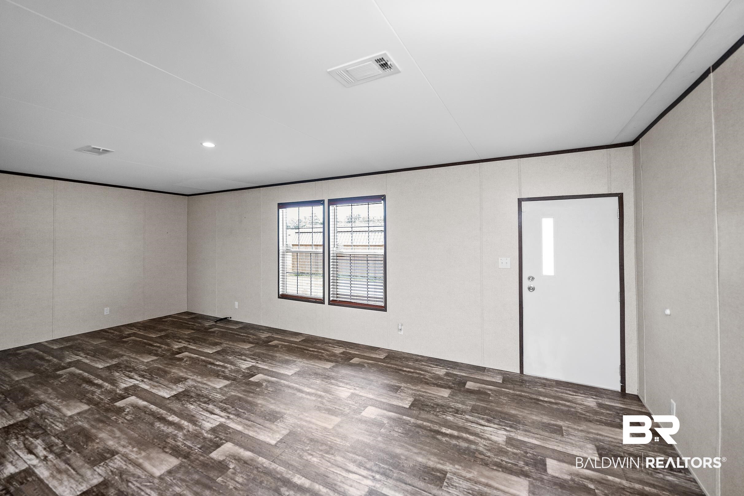 21601 Westside Loop Silverhill, AL 36576 - Photo 17 of 42 Spacious room featuring wood-finish flooring, two windows with blinds, a white entry door with a vertical glass insert, and recessed ceiling lighting
