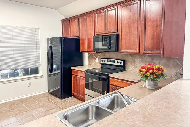 a kitchen with stainless steel appliances granite countertop a refrigerator sink and stove