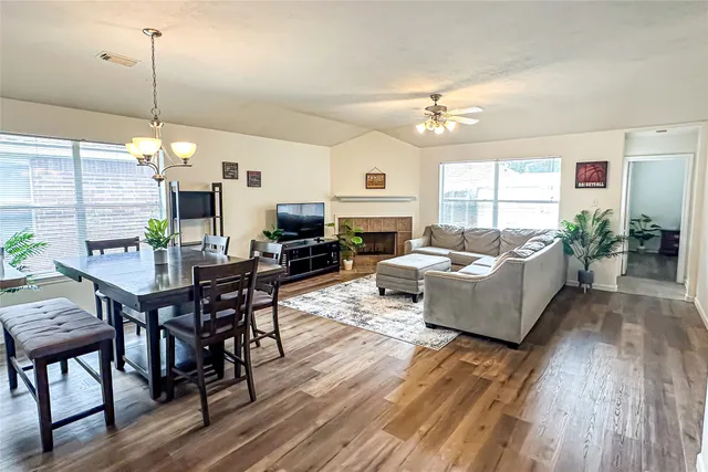 a living room with furniture dining table a rug potted plant and a window
