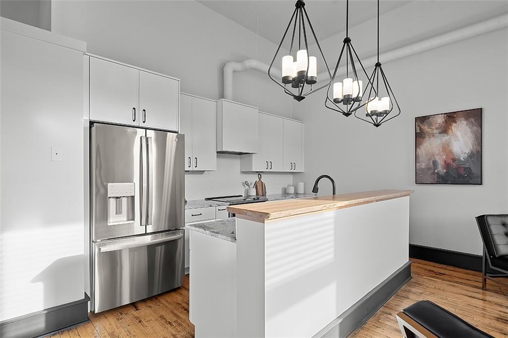 3080 Smallman Street Pittsburgh, PA 15201 - Photo 15 of 48 a kitchen with stainless steel appliances granite countertop a refrigerator a stove a sink dishwasher a dining table and chairs with wooden floor