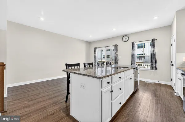 a kitchen with granite countertop white cabinets and wooden floor