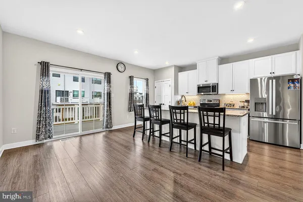 a kitchen with stainless steel appliances a dining table chairs refrigerator and cabinets
