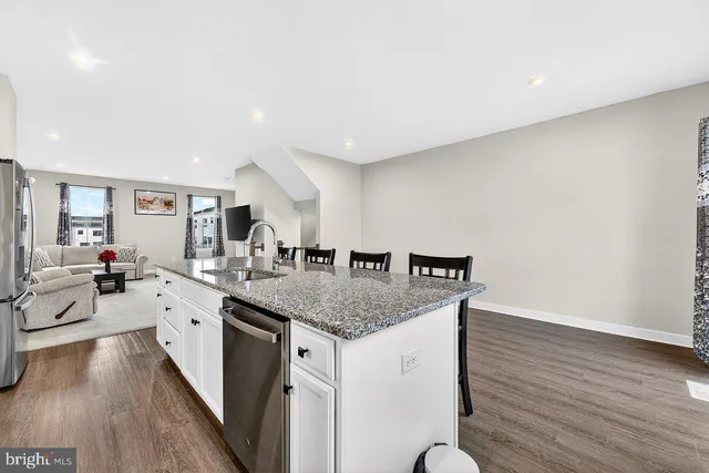 a kitchen with stainless steel appliances granite countertop a sink dishwasher and a stove with wooden floor
