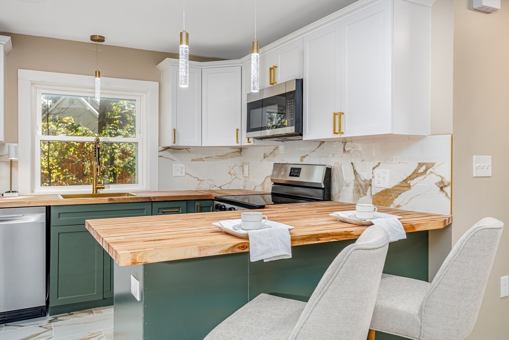 7 Groveland Street Ayer, MA 01432 - Photo 24 of 35 a kitchen with stainless steel appliances granite countertop a sink a stove a microwave a refrigerator and cabinets