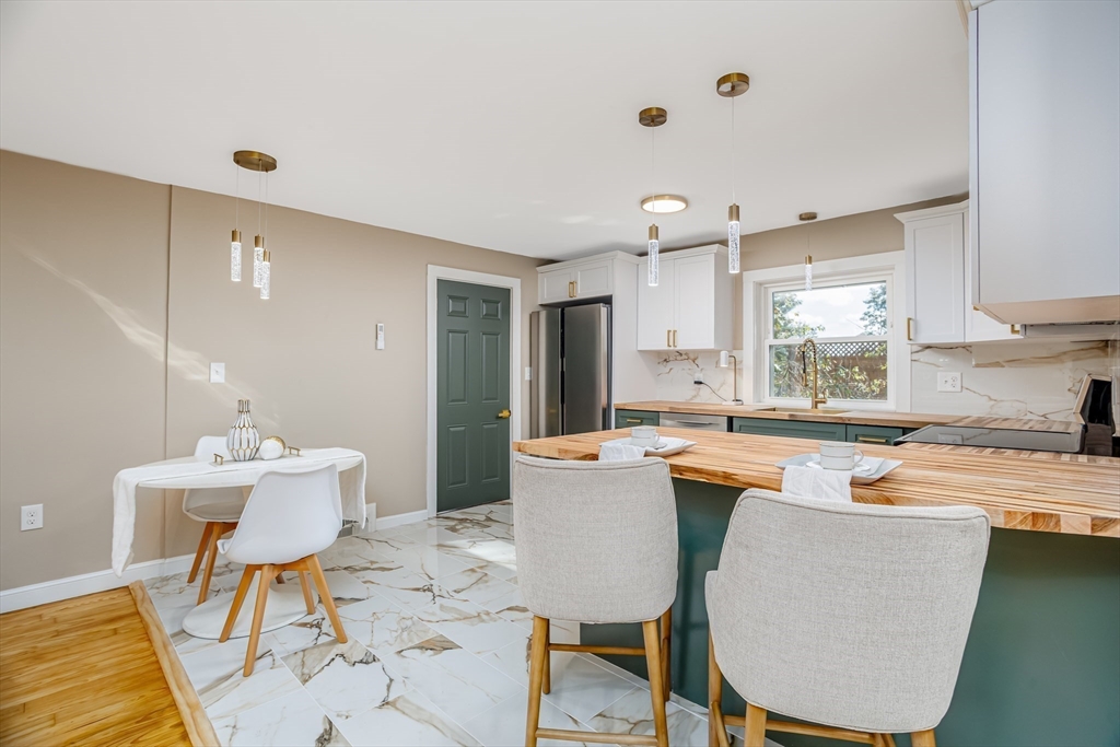 7 Groveland Street Ayer, MA 01432 - Photo 27 of 35 a kitchen with stainless steel appliances granite countertop a sink a stove a refrigerator dining table and chairs