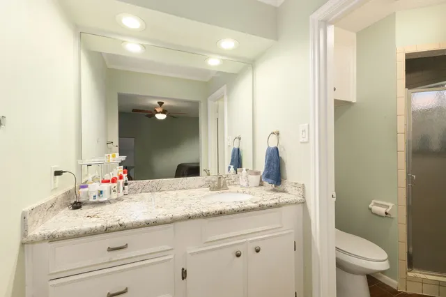 a bathroom with a granite countertop sink mirror and a toilet
