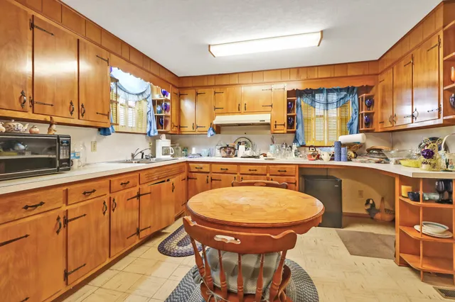 a kitchen with stainless steel appliances granite countertop a sink a stove a dining table and chairs