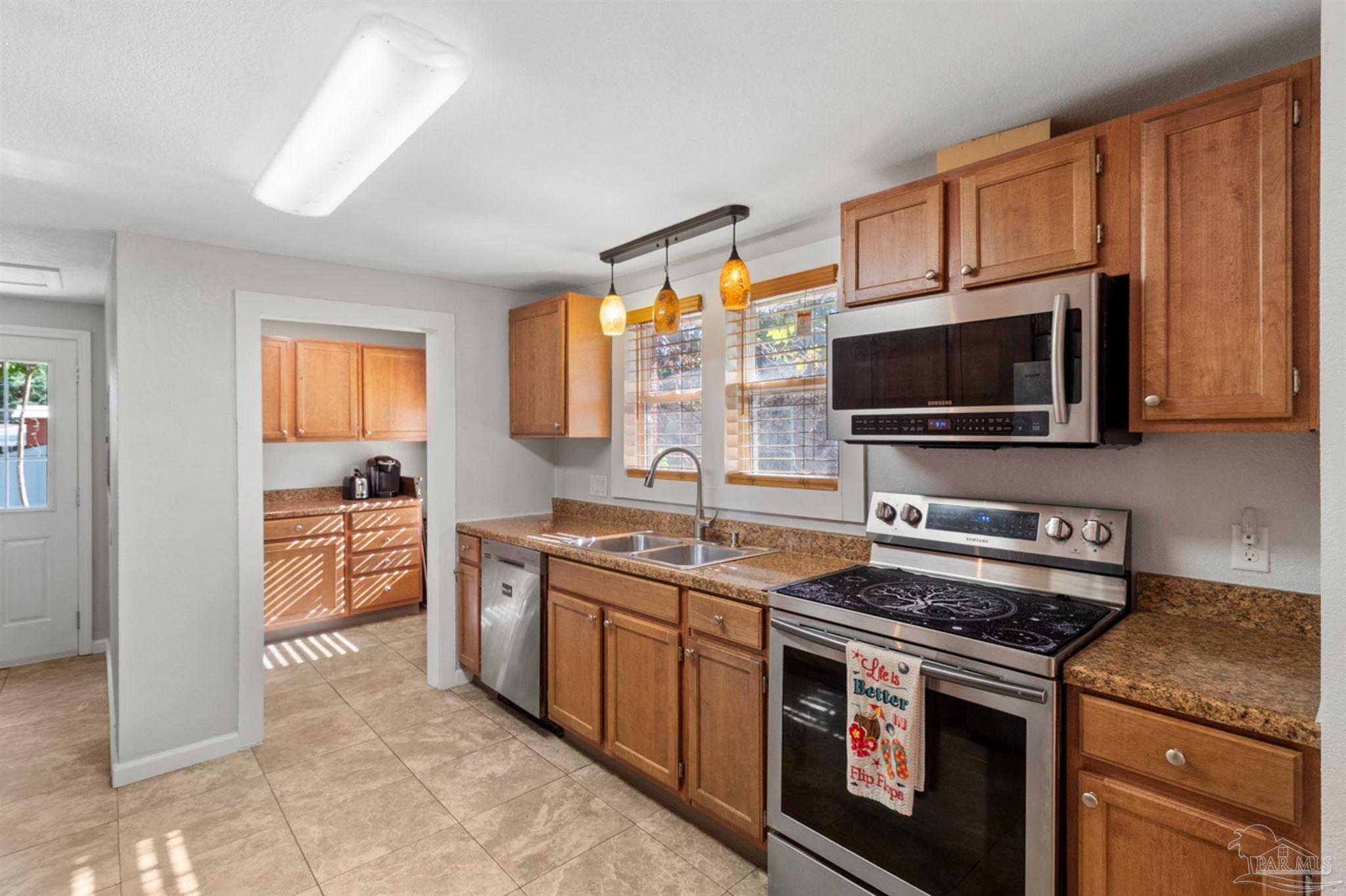 6608 Magnolia Street Milton, FL 32570 - Photo 4 of 36 a kitchen with stainless steel appliances a stove a sink and a microwave