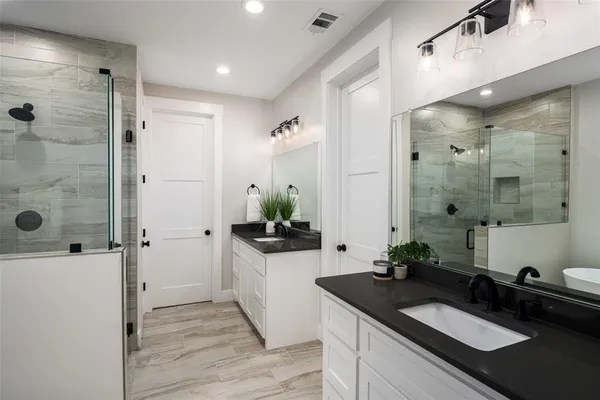 a spacious bathroom with a granite countertop sink a mirror and shower