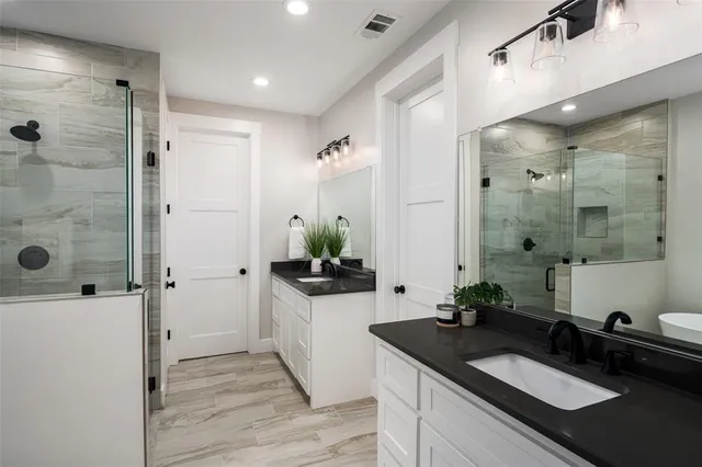 a spacious bathroom with a granite countertop sink a mirror and shower