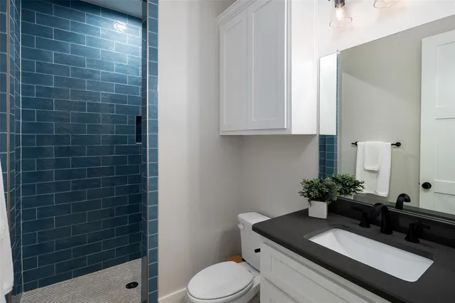 a bathroom with a granite countertop sink a toilet and mirror