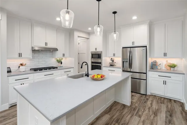 a kitchen with refrigerator a stove and white cabinets