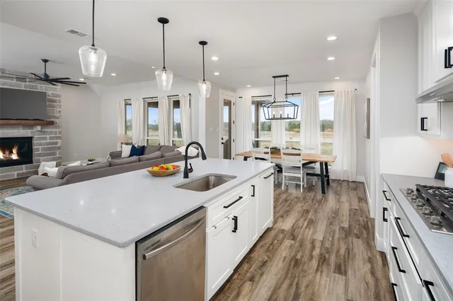 a kitchen with stainless steel appliances a stove a sink a oven a dining table and chairs