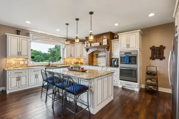 a kitchen with stainless steel appliances granite countertop a kitchen island a stove a table and chairs in it
