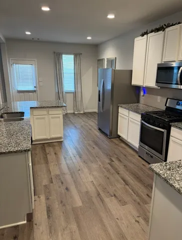 a kitchen with stainless steel appliances granite countertop a refrigerator stove microwave and sink