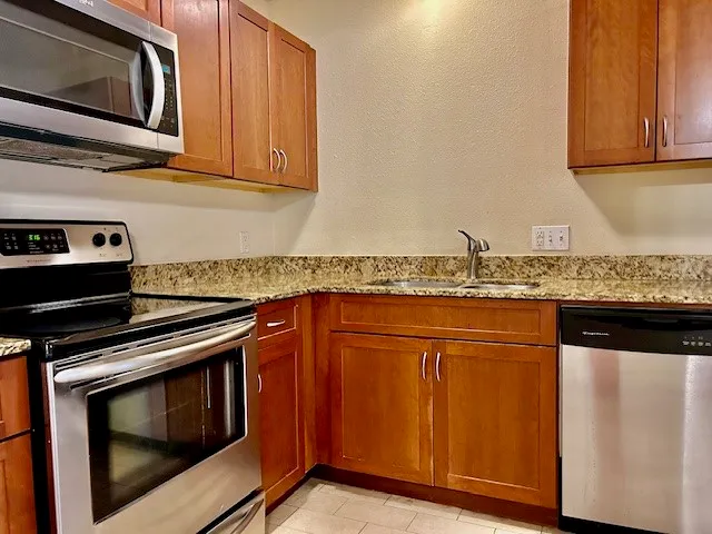 a kitchen with granite countertop stainless steel appliances and wooden cabinets