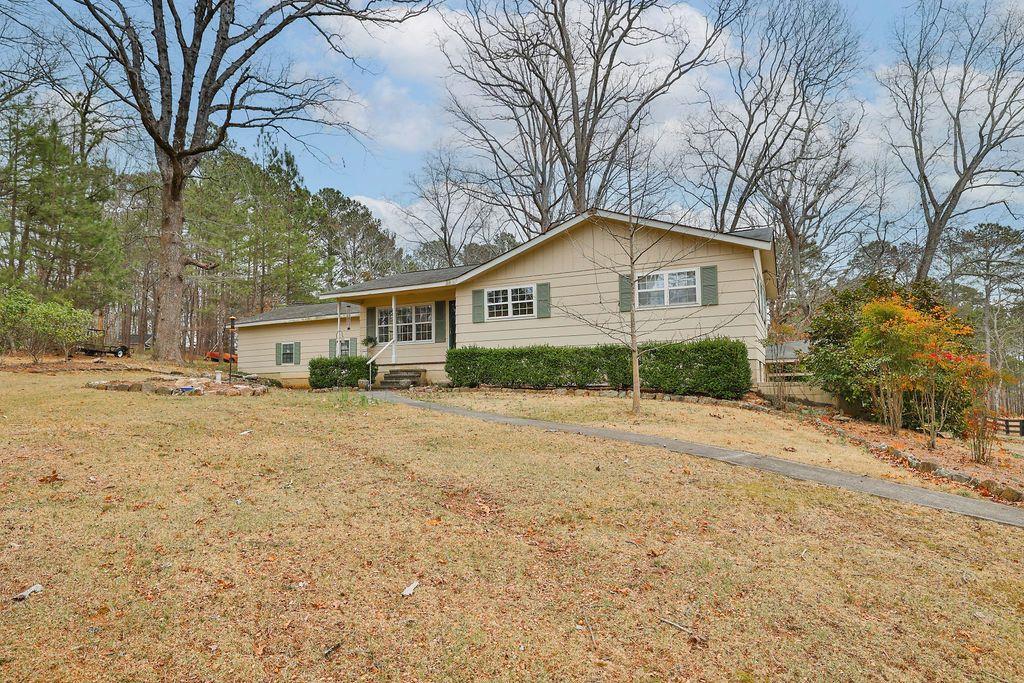 a view of a house with a yard and large tree