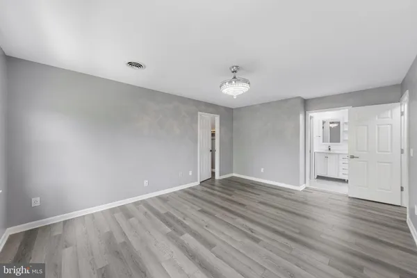 a view of an empty room with wooden floor and closet