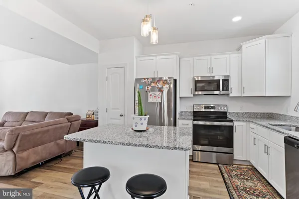 a kitchen with stainless steel appliances granite countertop a kitchen island a stove a sink a microwave and cabinets