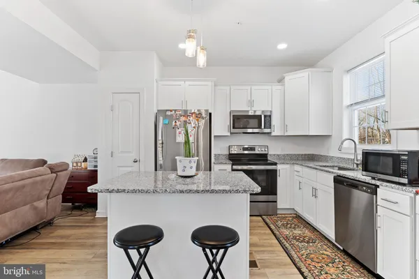 a kitchen with stainless steel appliances granite countertop a stove top oven a refrigerator a sink and white cabinets