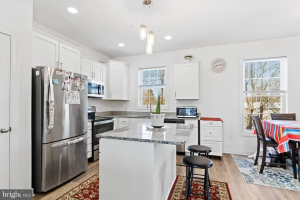 a kitchen with stainless steel appliances a refrigerator a stove a dining table and chairs