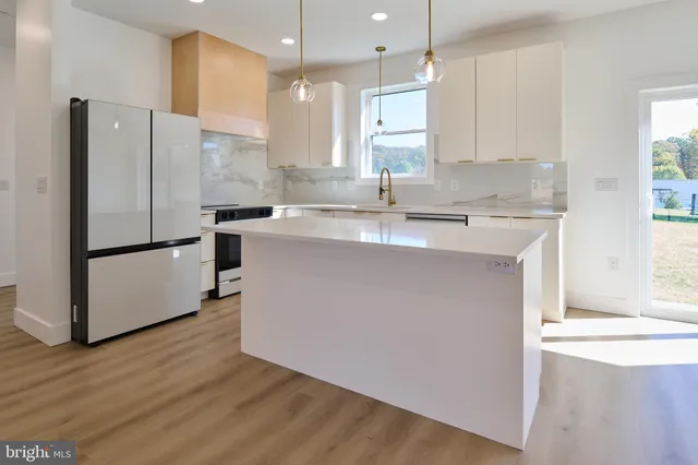 a open kitchen with white cabinets and wooden floor