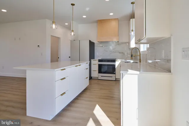 a large kitchen with granite countertop a white stove top oven and white cabinets