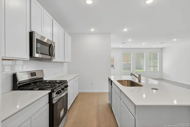 a kitchen with stainless steel appliances granite countertop a sink and a stove top oven with wooden floor