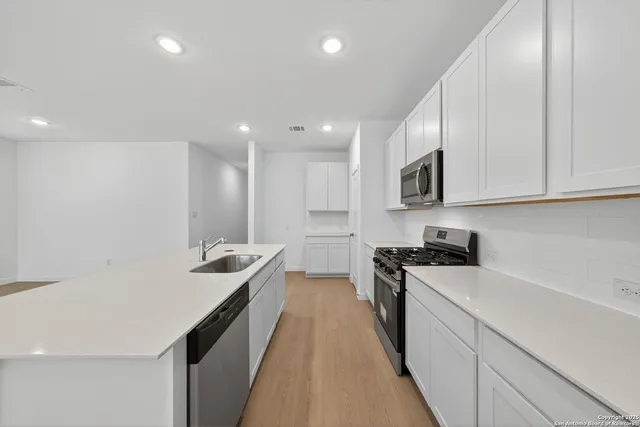 a kitchen with stainless steel appliances a sink stove and cabinets
