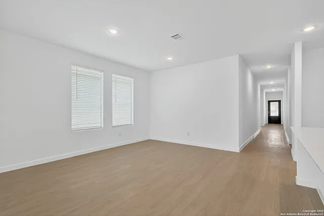 an empty room with windows and entrance to other room