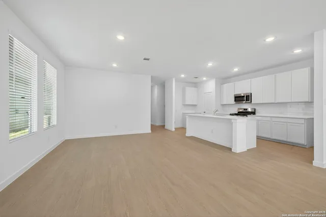 a kitchen with white cabinets and window