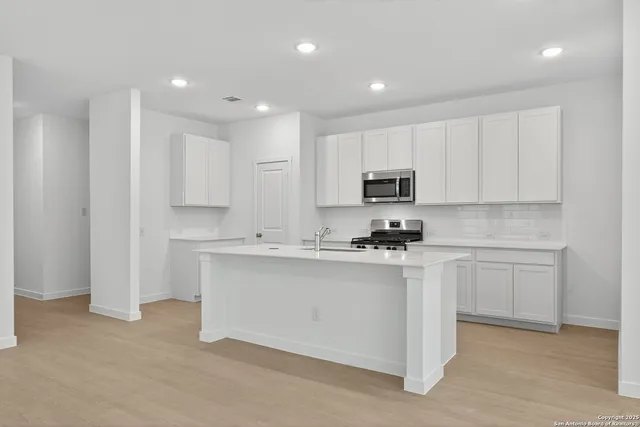 a kitchen with kitchen island white cabinets appliances and a sink