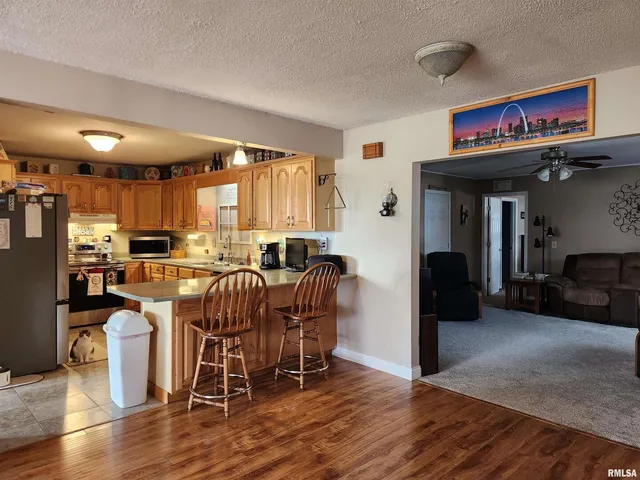 a kitchen with stainless steel appliances granite countertop wooden floors and wooden cabinets