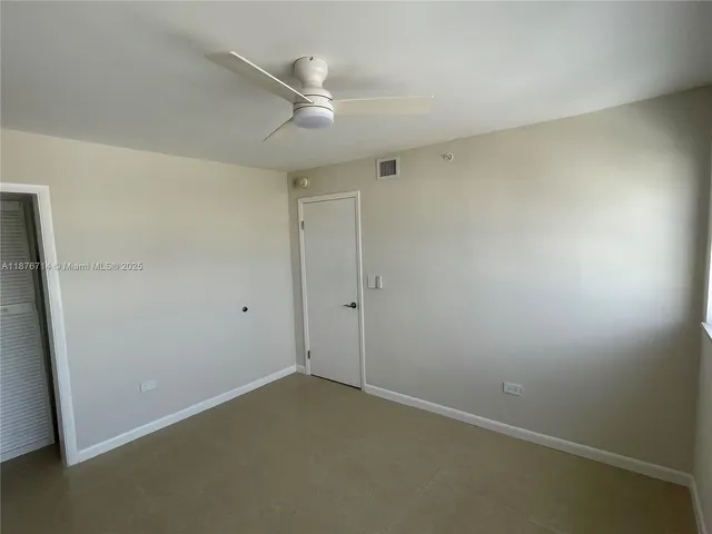 an empty room with a ceiling fan and a window