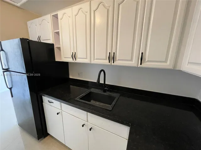 a kitchen with a sink a refrigerator and cabinets