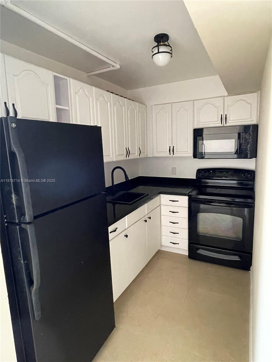 1881 Washington Avenue, Unit 15C Miami Beach, FL 33139 - Photo 20 of 30 a kitchen with stainless steel appliances a refrigerator stove and white cabinets