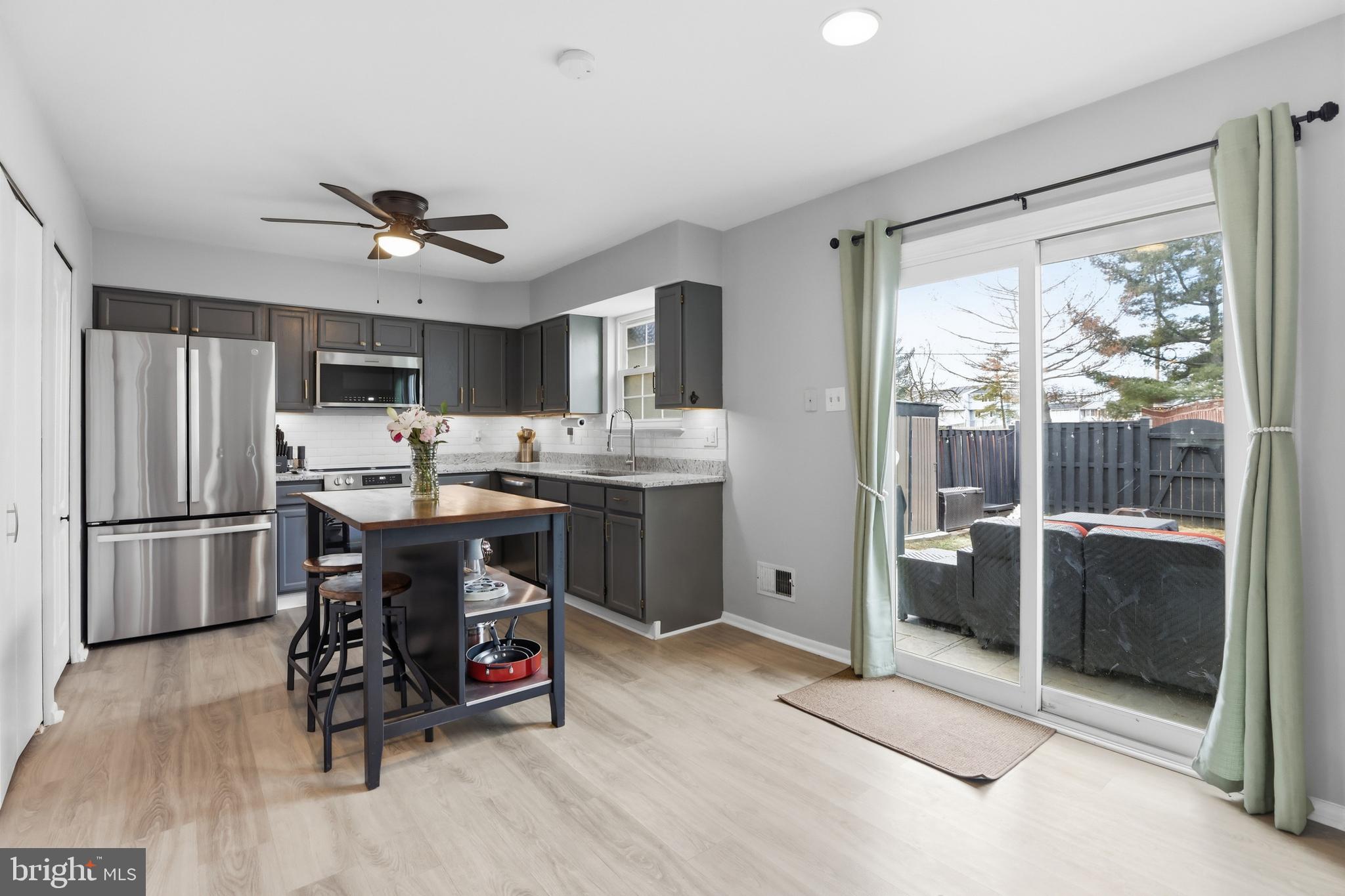 6844 Carnation Circle Frederick, MD 21703 - Photo 11 of 30 a open kitchen with stainless steel appliances granite countertop a refrigerator a stove a sink a dining table and chairs with wooden floor