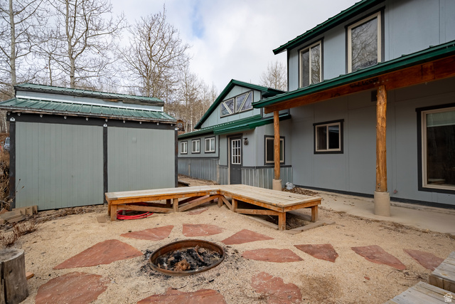 2029 West Tollgate Road Coalville, UT 84017 - Photo 3 of 36 Exterior featuring a covered patio with log columns, a gravel patio area with large stone pavers, and a built-in fire pit