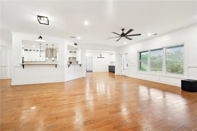 a view of an empty room with kitchen and window