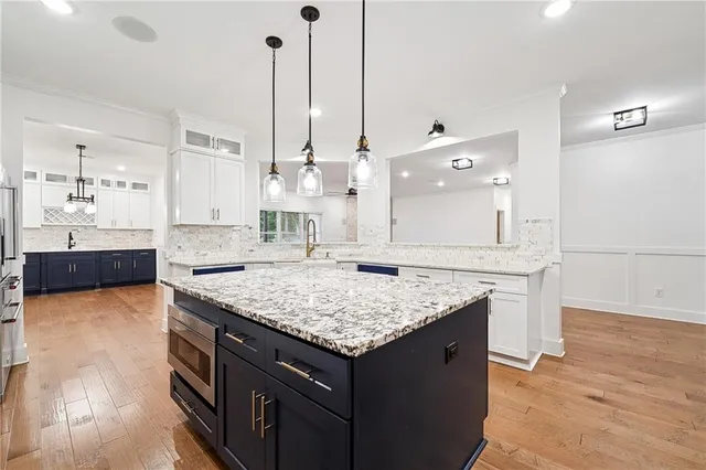 a kitchen with stainless steel appliances granite countertop a sink a stove and a wooden floor