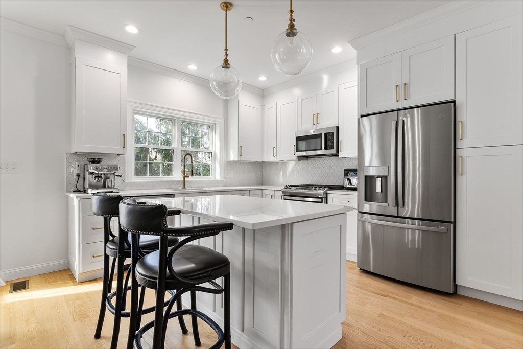 68 Prospect Street, Unit 14 Peabody, MA 01960 - Photo 2 of 29 a kitchen with stainless steel appliances granite countertop a dining table chairs refrigerator and microwave