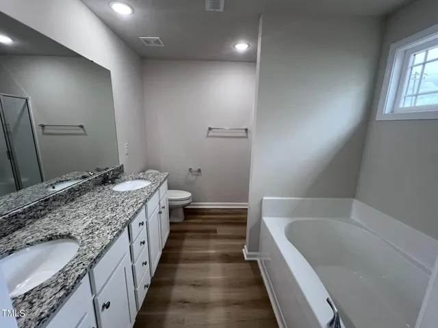 a bathroom with a granite countertop double vanity sink and mirror with bathtub