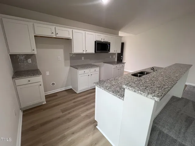a kitchen with granite countertop a sink stove and microwave